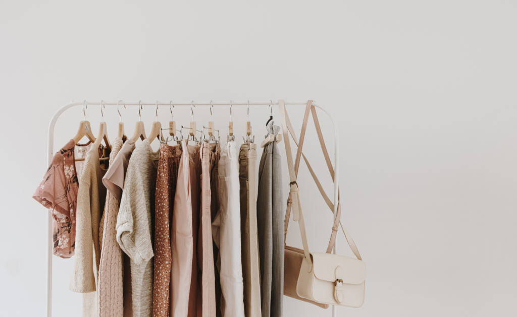 Minimalist clothing rack with neutral-toned clothes and accessories for capsule closet