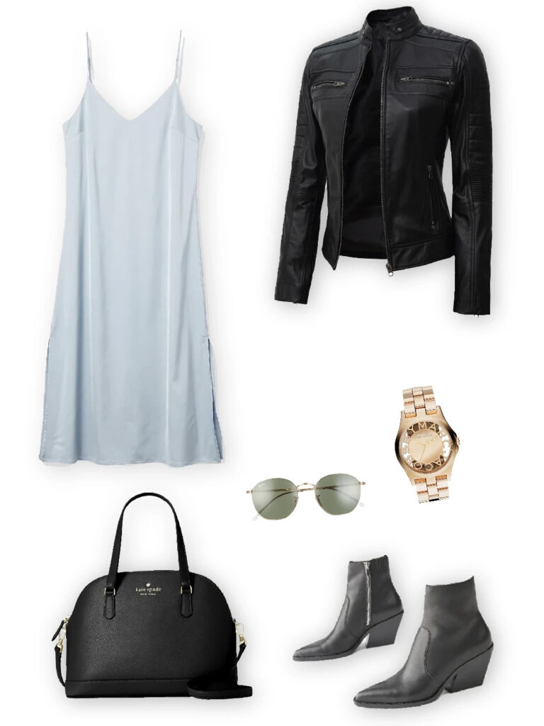 Leather jacket layered over a light blue slip dress, paired with black ankle boots, a structured handbag, a gold watch, and aviator sunglasses.